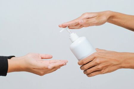 School teacher using alcohol spray or hand sanitizer to student before enter school taking care of hand hygiene during COVID-19 pandemicの写真素材
