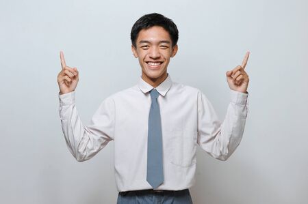 Indonesian Senior Student wearing uniform with two fingers pointed up, isolated on grey backgroundの写真素材