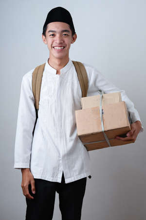 Portrait Asian Muslim man against on grey background wearing muslim clothes and holding box of...