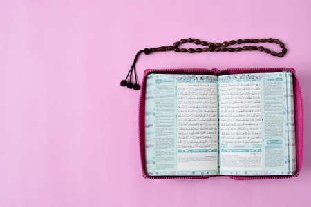 Top View Flatlay of Muslim Holy Qur'an and prayer beads on pink background colorの写真素材