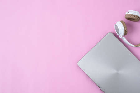 Top View Flatlay of modern wireless headphone and minimalist laptop on pink color workspace