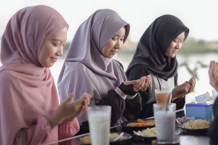 Muslim asian friends pray together when breaking fast at cafeの写真素材