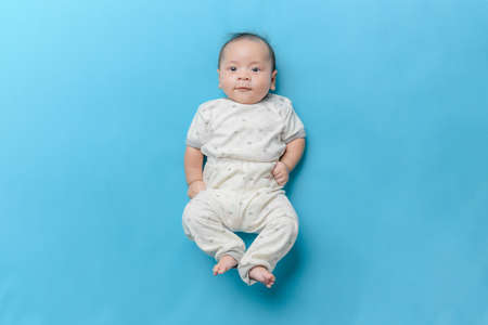 Portrait of Asian baby boy lying on light blue with a copy spaceの写真素材
