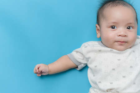 Portrait of Asian baby boy lying on light blue with a copy space