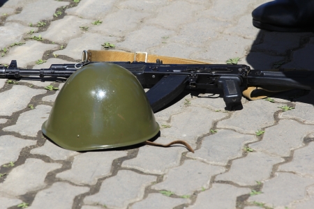 helmets and assault rifles lay on the groundの写真素材
