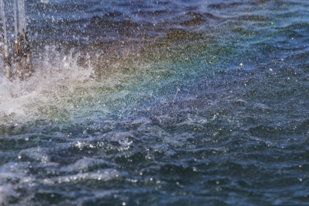 spray and a rainbow over the waterの写真素材