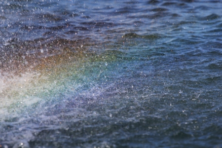 spray and a rainbow over the waterの写真素材