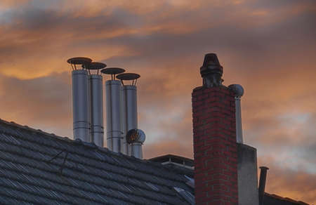 Flue stacks and chimneys on a roof at sunsetの写真素材