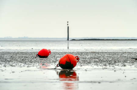 The Wadden Sea and buoys at low tide in Norddeichの写真素材