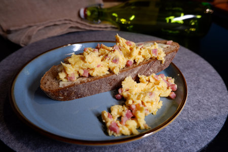 Bread with scrambled eggs and bacon bits on a plateの写真素材