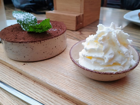 Tiramisu and whipped cream on a wooden plate