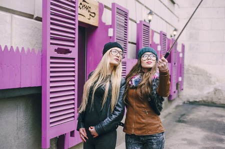 two beautiful girls are photographed on the street in hats and classy jacketsの写真素材
