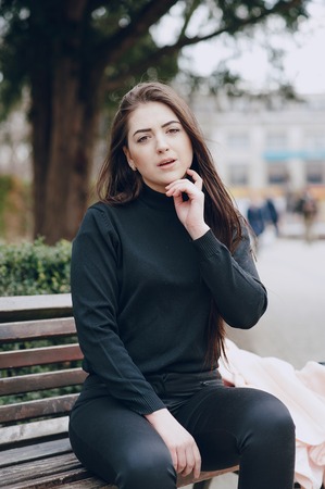 beautiful young model sitting on a bench and posing