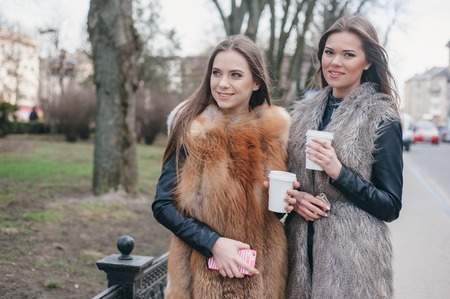 young model walk around town in fur coats in coffee cupsの写真素材