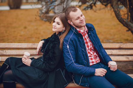 Couple walking through the city, sitting on the bench, photographed and drinking coffeeの写真素材