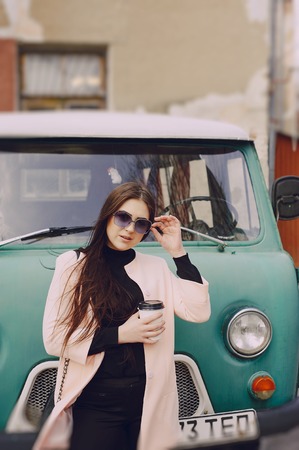 girl near the car with a mug of coffee in glassesの写真素材