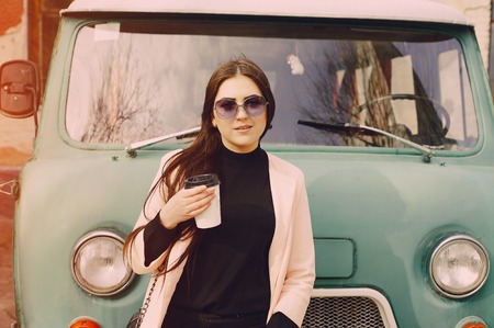 girl near the car with a mug of coffee in glassesの写真素材