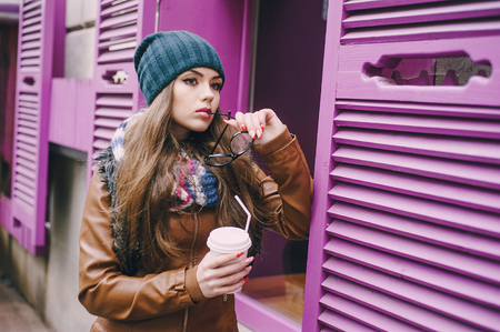 two beautiful girls walk around town fashionably and stylishly dressed with a Cup of coffeeの写真素材