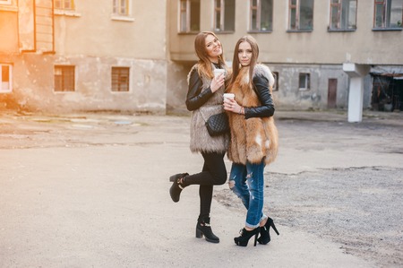young model walk around town in fur coats in coffee cupsの写真素材
