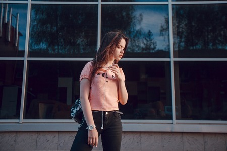 stylish girl walking in the evening city with a phone and a headsetの写真素材