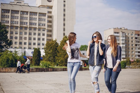 three beautiful girls walking in the park and take pictures on your phoneの写真素材