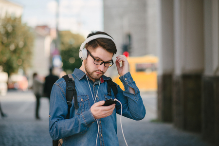 boy with headphones, phone and tablet walks in the city and parkの写真素材