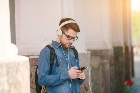 boy with headphones, phone and tablet walks in the city and parkの写真素材