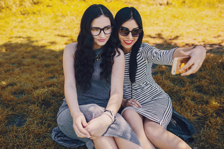 Two stylish girl walking in the park and make selfieの写真素材
