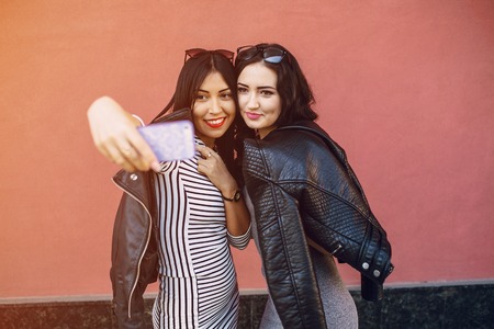 Two stylish girl walking in the park and make selfieの写真素材