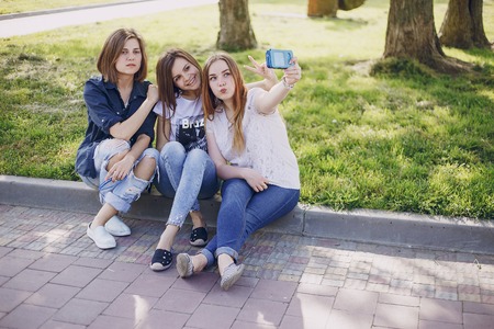 three beautiful girls walking in the park and take pictures on your phone