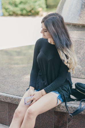 girl walking in the city with phone and backpack and listening to musicの写真素材