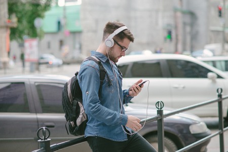 boy with headphones, phone and tablet walks in the city and parkの写真素材