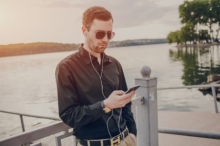 A guy in a nice town, walking, listening to music and taking pictures themselves on the phoneの写真素材