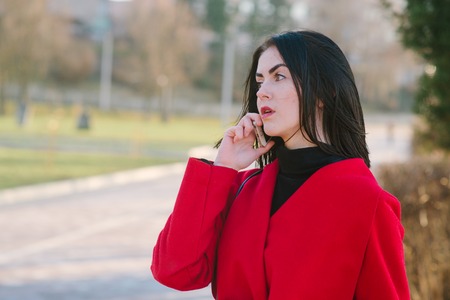 Girls walking around town on a sunny day with phones sitting on a bench and drink coffeeの写真素材