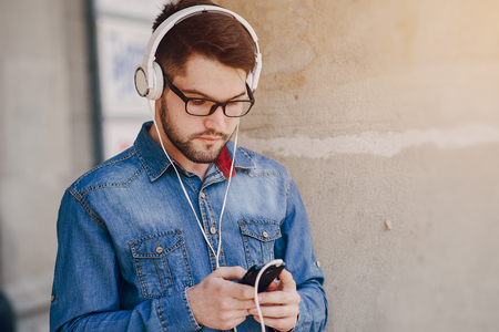 boy with headphones, phone and tablet walks in the city and parkの写真素材