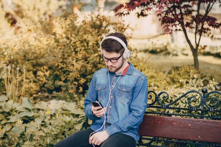 boy with headphones, phone and tablet walks in the city and parkの写真素材