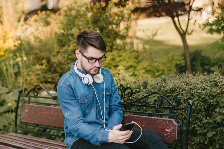 boy with headphones, phone and tablet walks in the city and park