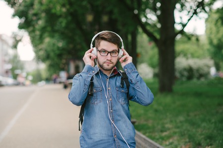 boy with headphones, phone and tablet walks in the city and parkの写真素材