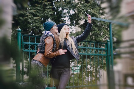 two beautiful girls are photographed on the street in hats and classy jacketsの写真素材