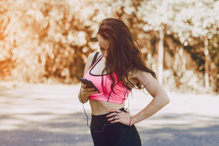 sports girl in the park performing various exercises. uses communication