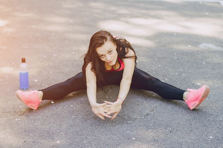 sports girl in the park performing various exercises. uses communication