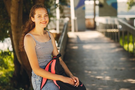 a beautiful young girl sitting in a summer cityの写真素材