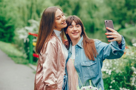 Beautiful girlfriends walking in the park and doing a photo.