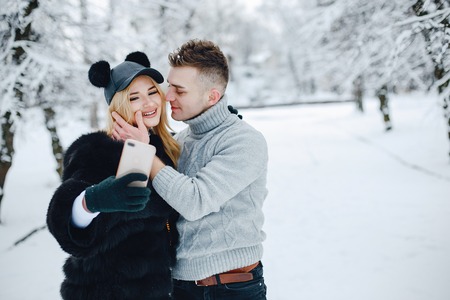 Stylish young couple in winter park happy and joyful