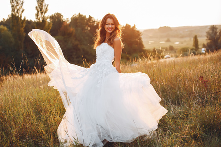 Beautiful bride walking in a summer fieldの写真素材