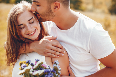 Cute couple in a park. Lady in a white dress. Girl with bouquet of flowersの写真素材