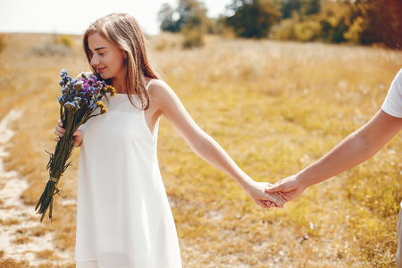 Cute couple in a park. Lady in a white dress. Girl with bouquet of flowersの写真素材