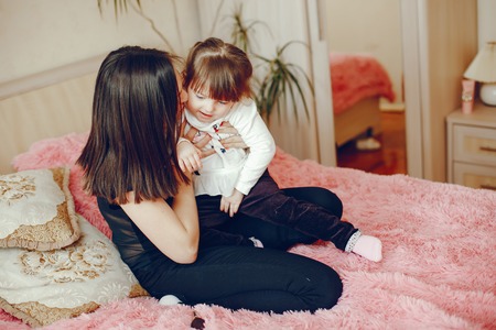 Mother with daughter sitting on a bedの写真素材