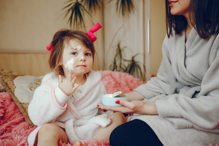 Mother with daughter sitting on a bedの写真素材