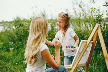 Mother with daughter drawing in a parkの写真素材